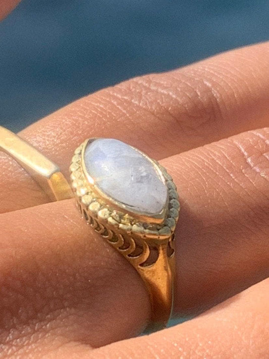 Könnte beinhalten: Ein goldener Ring mit einem großen, ovalen Mondstein, der in einem detaillierten, verzierten Design gefasst ist.